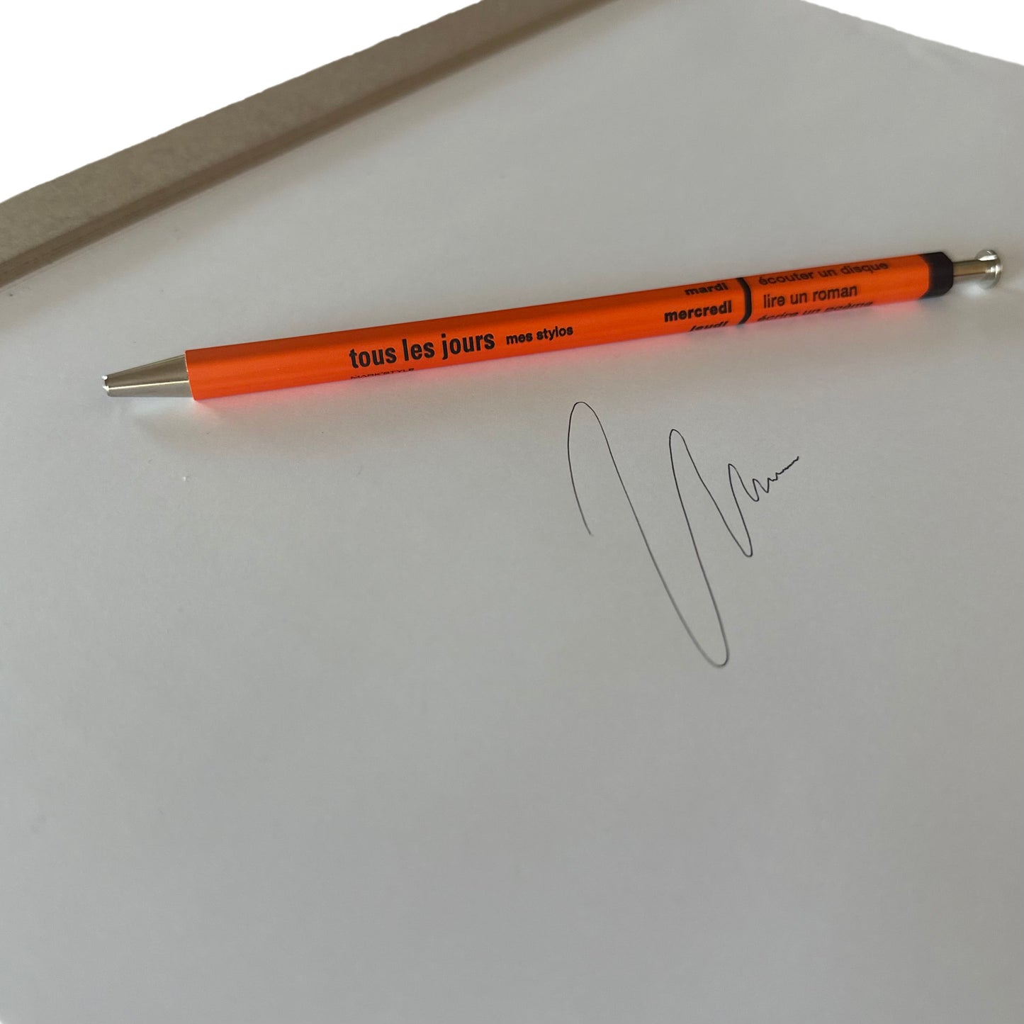 An image of an orange pen on a white piece of paper with an ink drawing on it.