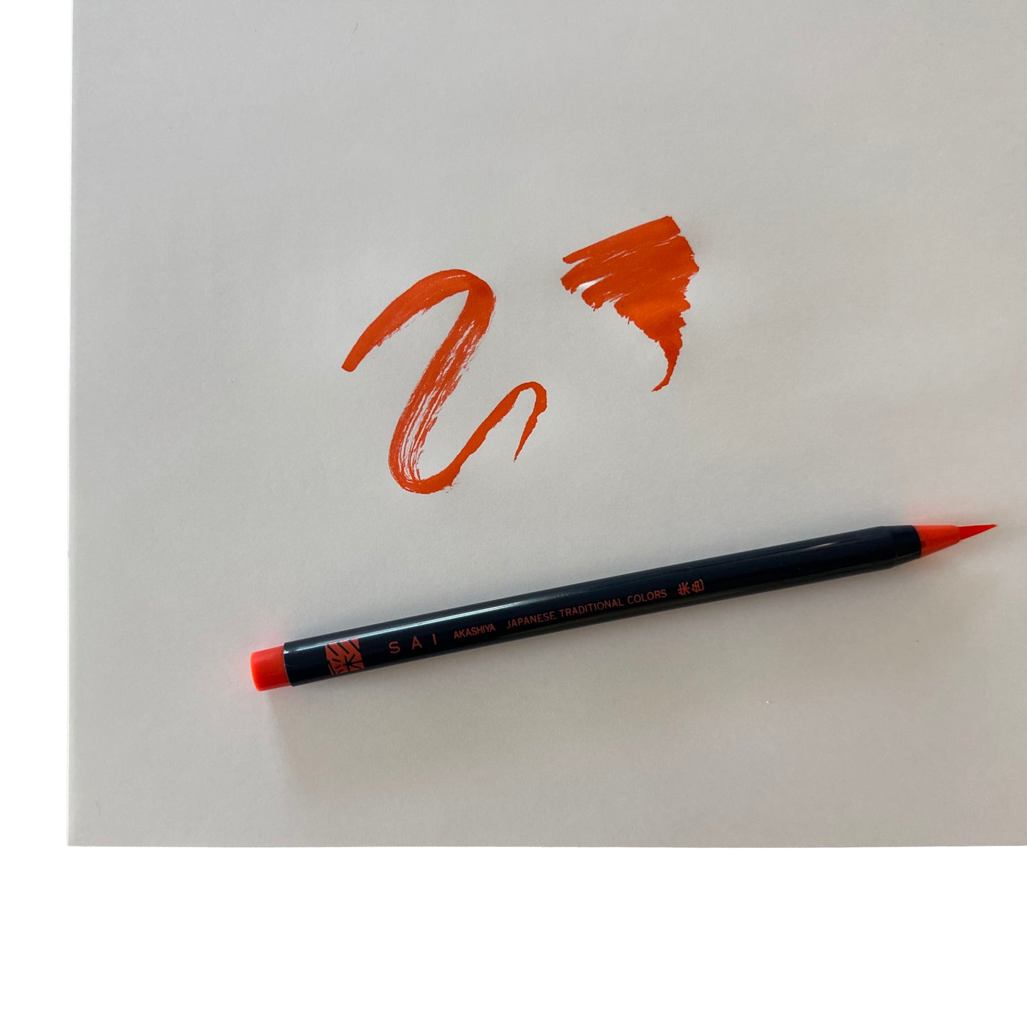 Orange brush pen with orange drawing on white paper
