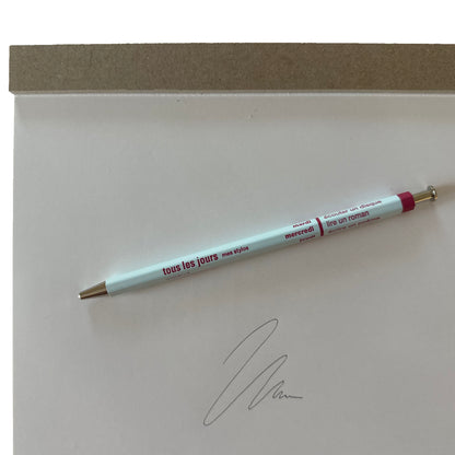 Light blue pen with red text on a white surface