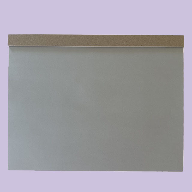 Gray drawing pad with a brown accent on a light purple background