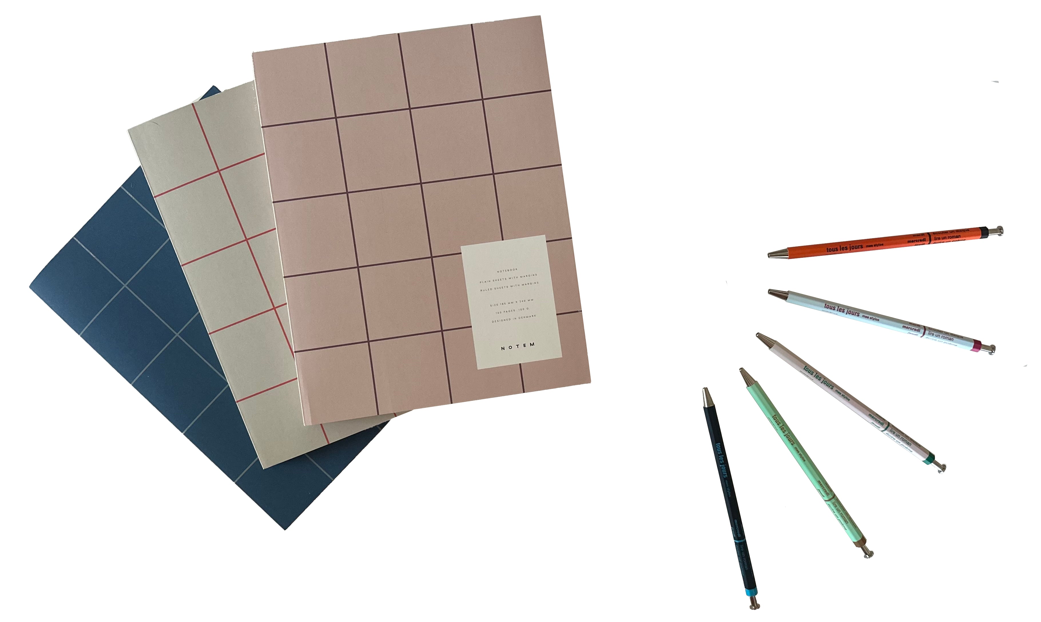 Three notebooks with grid patterns and a set of colored pencils on a white background