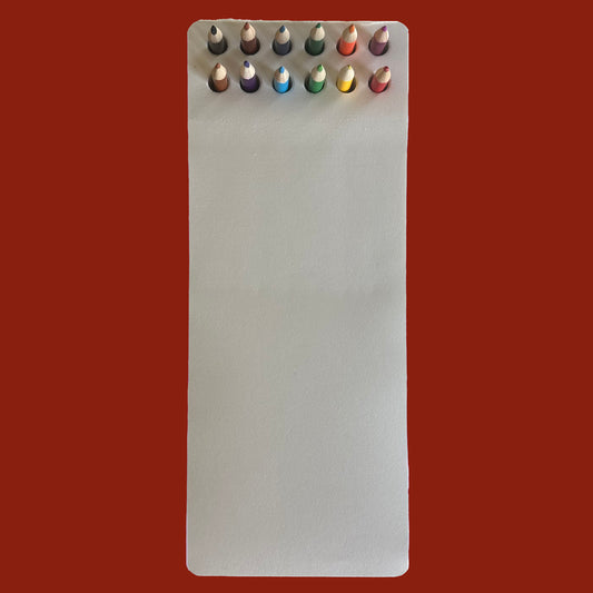 Set of colored pencils in a white notepad against a red background