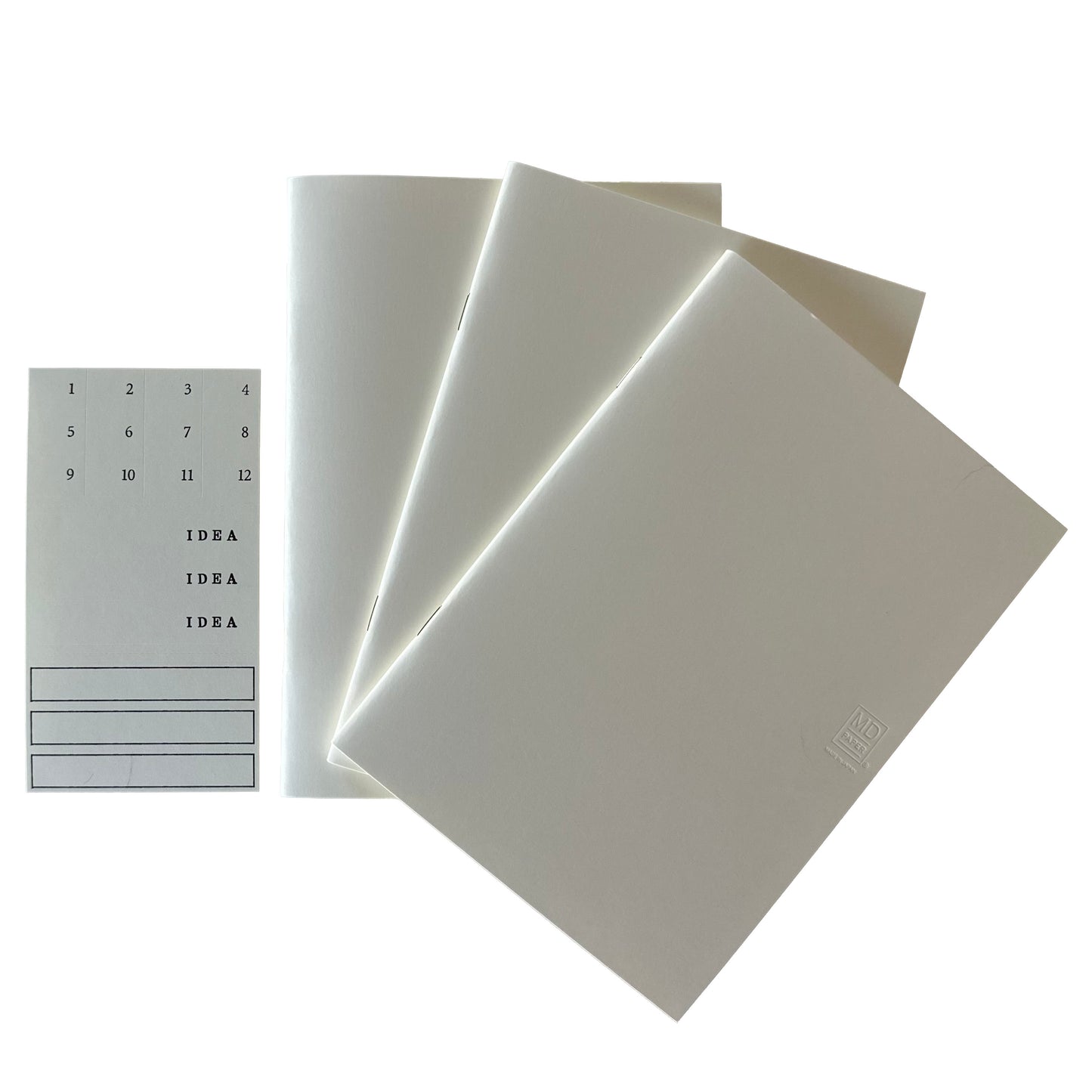 Set of three white notebooks with a small label pack on a white background