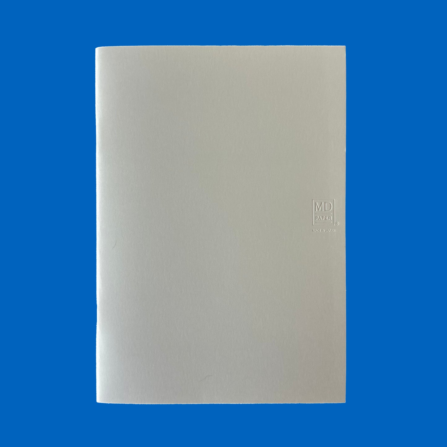 Beige notebook with MD logo on a blue background