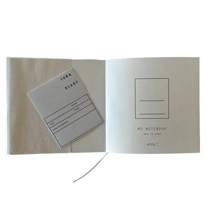 Open notebook with label stickers titled 'Idea Diary' on a white background