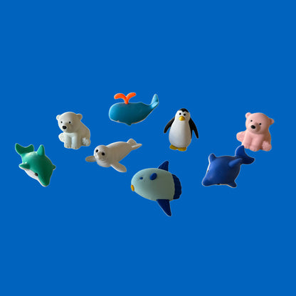 Set of toy animal erasers including a polar bear, penguin, seals, and dolphins on a blue background