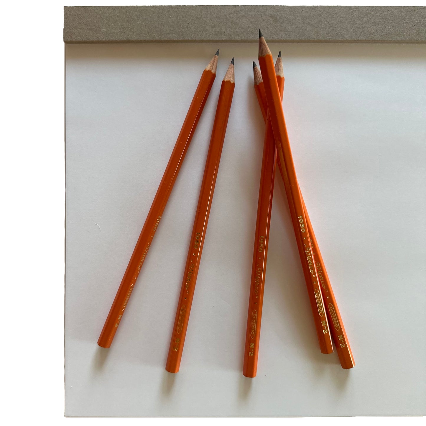 Orange pencils on a white surface with a gray background