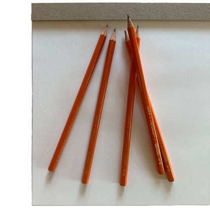 Orange pencils on a white surface with a gray background
