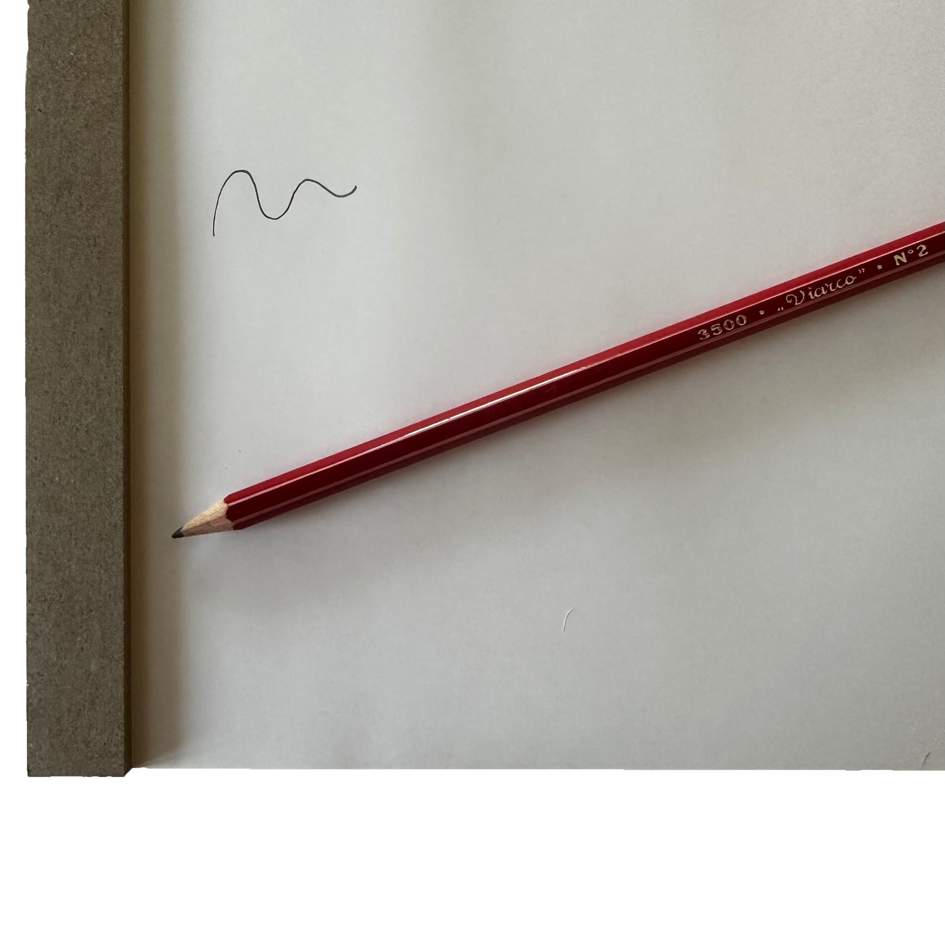 Red pencil on a white sheet of paper with a wavy line drawn.