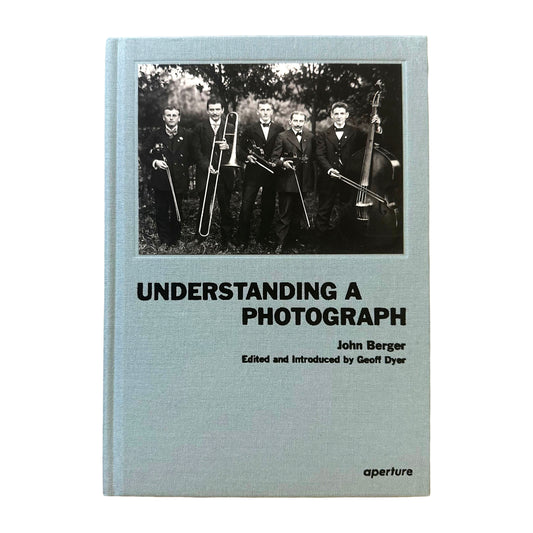 Book cover of 'Understanding a Photograph' by John Berger with a black and white photo of men in suits.